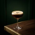 An Espresso Martini with a thick crema foam and three coffee beans